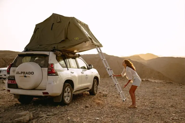 Femme qui déplie une tente de toit sur un 4x4 à Oman