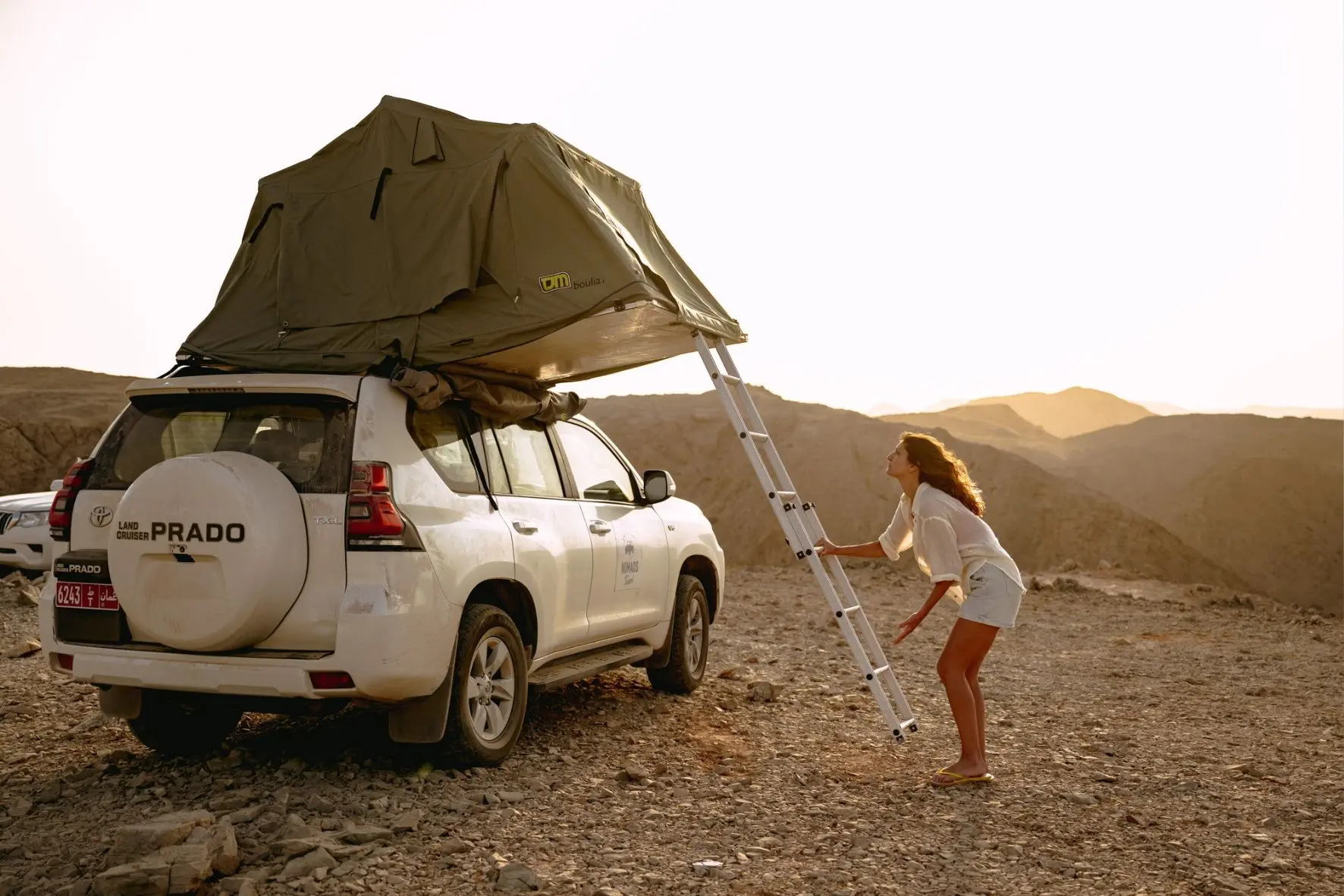 Femme qui déplie une tente de toit sur un 4x4 à Oman