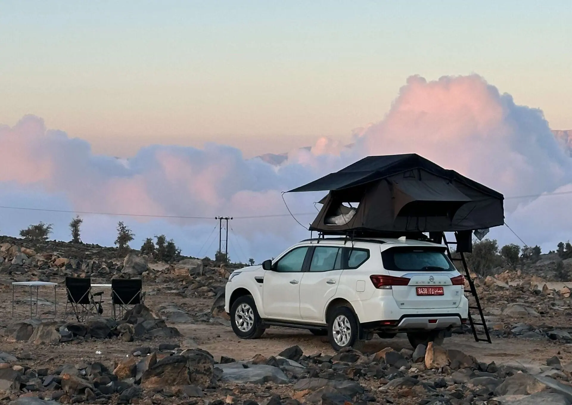4x4 avec une tente de toit dans les montagnes au dessus des nuages